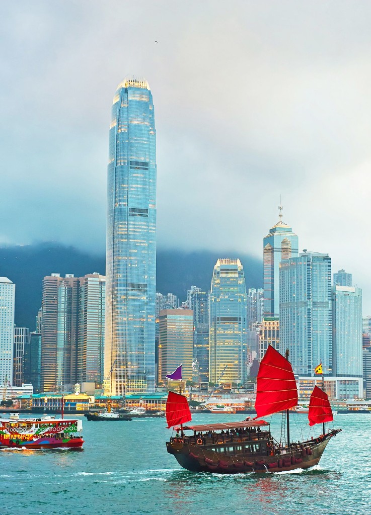 Traditional junk boat with red sails on Victoria Harbour with Hong Kong skyline